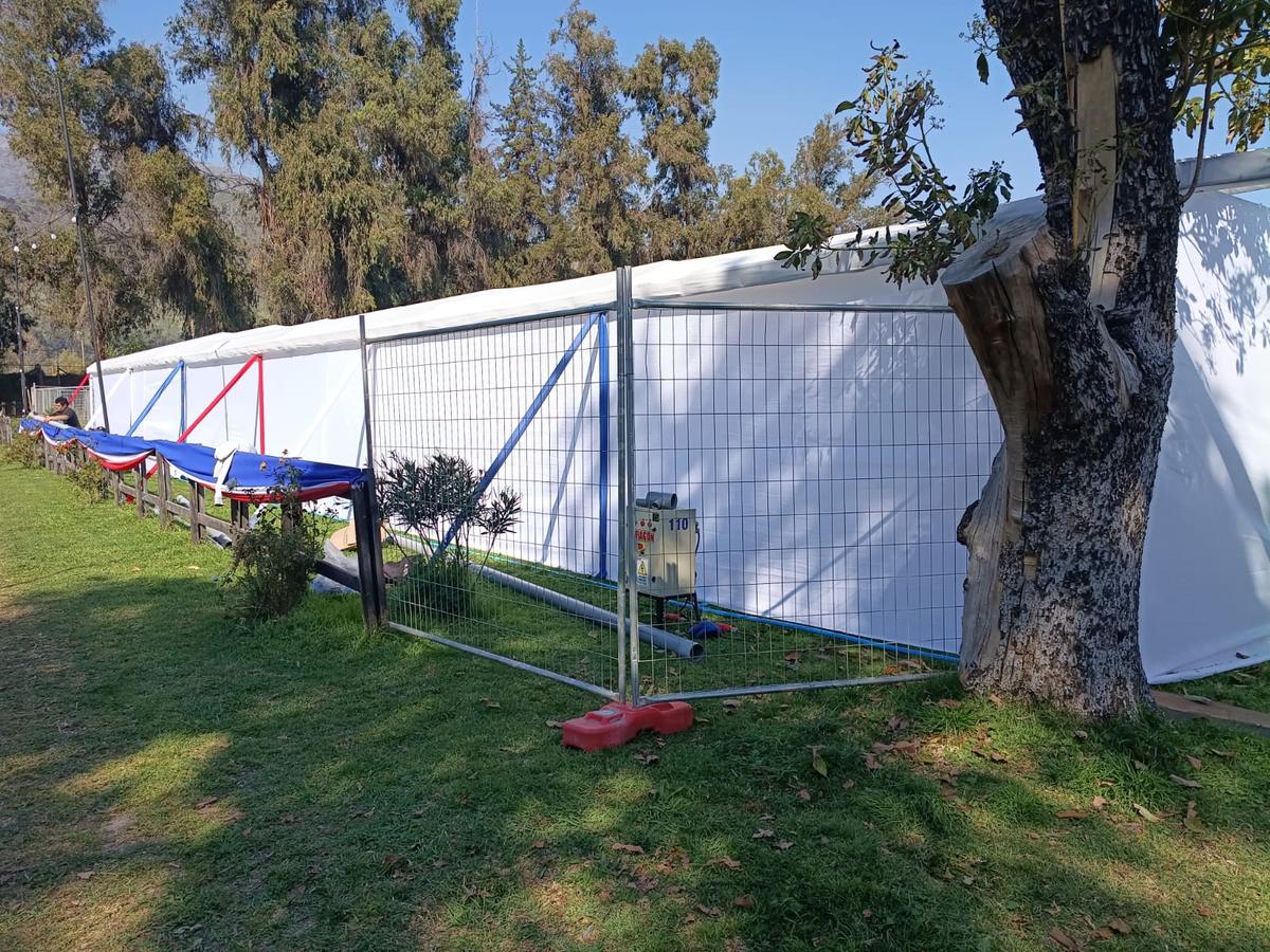 Tablero eléctrico protegido con reja junto a una carpa